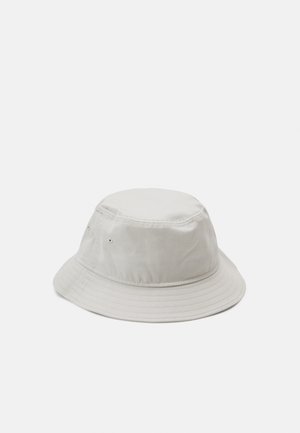 Lys grå bucket hat med en rund krone og bred, nedadgående skygge. Fremstillet af stof med en glat tekstur, der har ventilationsøjer.