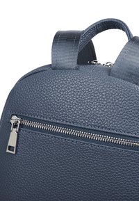 Ciemnoniebieski plecak o fakturowanej powierzchni z przednią kieszenią na zamek błyskawiczny, z gładkim uchwytem zamka i podwójnymi fabricznymi paskami.