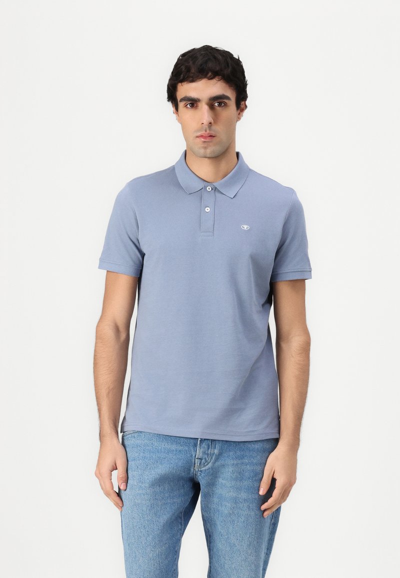 Lys blå polo skjorte lavet af bomuld, med en klassisk krave, korte ærmer og et lille broderet logo på brystet. Sammen med blå jeans.