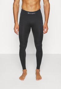 Svarte treningstights laget av elastisk materiale, med en bred midjebånd og en hvit "Champion"-logo øverst.