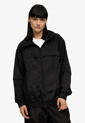 Giacca nera con cerniera, cappuccio e due tasche anteriori. Realizzata in tessuto lucido e strutturato con polsini elasticizzati. Design semplice e moderno.