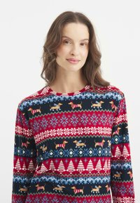 Camiseta de manga larga con un fondo azul oscuro y secciones estampadas en rojo y blanco, adornada con teckels en atuendo festivo y copos de nieve.