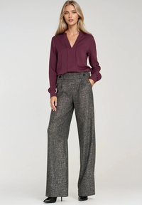 Bordowa bluzka z dekoltem w serek i długimi rękawami, zestawiona z szerokimi spodniami w szary kratkę z zapięciem w pasie na guziki i kieszeniami.