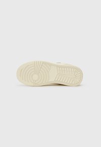 Lys beige sneaker såle med et teksturert mønster, som har sirkulære og lineære design for grep. Glatt materiale og avrundet form.