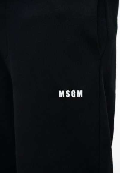Pantalon en tissu noir avec un petit logo MSGM blanc imprimé sur la partie supérieure de la cuisse, près d'une poche latérale.