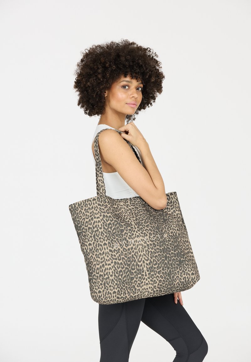 Sac fourre-tout en tissu imprimé léopard beige et marron, doté de deux anses solides et d'une forme décontractée.