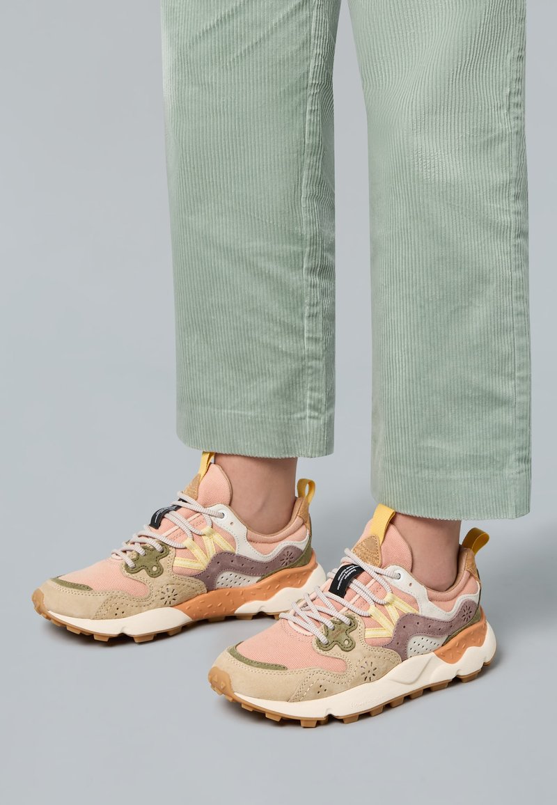 Mehrfarbige Turnschuhe aus pinken, beigen und olivgrünen Materialien. Texturiertes Obermaterial, gepolsterter Schaft und robuste Gummisohle sind deutlich erkennbar.