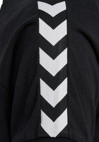 Zwarte sweatshirt met een zijpaneel met een wit chevronpatroon. De stof is glad en het ontwerp omvat contrasterende texturen.