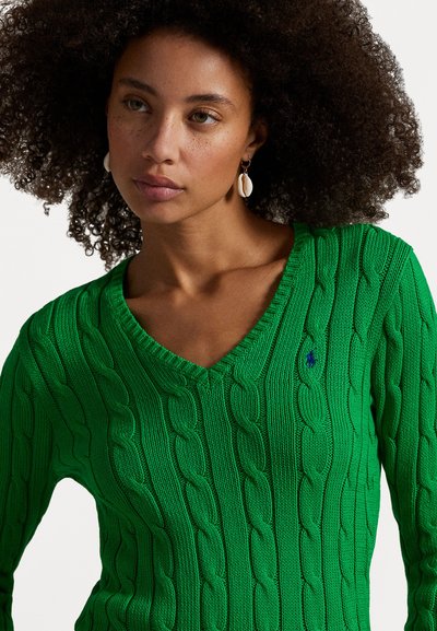 Green cable-knit sweater with a V-neck design, featuring a small blue logo and textured fabric. The sweater has a close-fit silhouette.