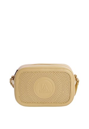 Bolso bandolera rectangular beige con panel frontal perforado y parche redondo con logotipo en relieve, correa ajustable sobre fondo blanco.