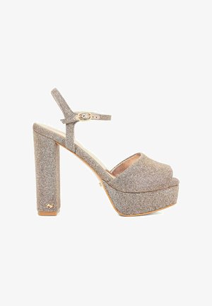 Sandale à talons hauts avec un tissu paillettes beige, bout ouvert, bride de cheville réglable et un talon épais en bloc avec une accent en or.