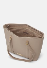 Beige faux læder toilettaske med guldfarvet hardware, rund form, åben top og stofforet inderside med en lynlåslomme.