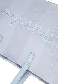 Błękitna, teksturowana torba z wytłoczonym napisem. Posiada dwie skórzane uchwyty i schludny, zorganizowany design.