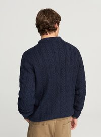 Maglione blu scuro a trecce con collo rotondo e motivo testurizzato. Polsini e orlo a coste per una vestibilità aderente.
