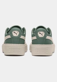 Green leather sneakers with a thick cream sole, featuring a PUMA logo on the heel and side, textured accents, and a padded collar.