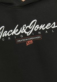 Sudadera negra con logo de script blanco "Jack & Jones" y detalle rojo "Creado en Copenhague". Tejido suave, capucha ajustable, estilo casual.