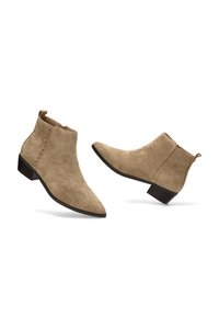 Botas de tobillo de ante color beige con puntera puntiaguda y tacón bajo. Presentan remaches decorativos a lo largo del lateral y un cierre de cremallera en la parte trasera.