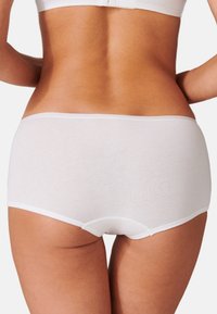 Shorts en coton blancs ayant une texture lisse, dotés d'une taille élastique douce et d'un design minimaliste. Aucun motif ou accent notables.