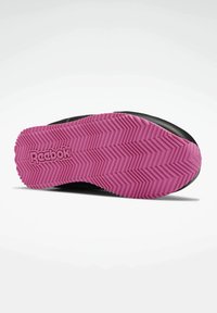 Semelle de chaussure avec motif à rayures zigzag roses et logo Reebok, montrant le design et la texture de l'adhérence.