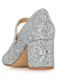 Zapato de tacón alto plateado con brillo, punta redonda y tacón grueso. Textura de superficie brillante con un interior de cuero elegante.