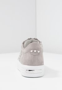 Sneaker in suede grigio chiaro con suola platform bianca, decorata con piccole perle bianche sul tallone e sul lato, su una superficie bianca.