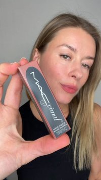 Rouge à lèvres mat dans un emballage rectangulaire flexible, de couleur rose-brun avec une étiquette noire et un texte blanc, tenu dans une main.