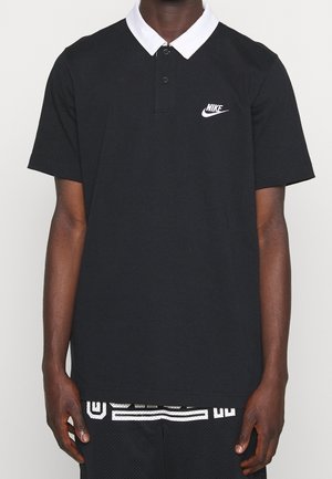Sort polo i bomuld med hvid krave og lille hvid Nike-logo på venstre bryst. Kortærmet, almindelig pasform.