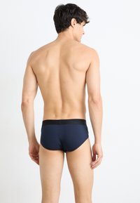 Marineblå herrebokser med svart elastisk midjebånd, laget av et glatt og stretchy materiale, med en tettsittende og formtilpasset design.