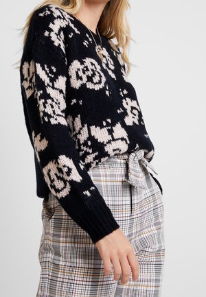 Gebreid sweater in marineblauw met beigetinten bloemmotieven, met een relaxte pasvorm en ribbenmanchetten. Gecombineerd met een hoogwaardige pantalon met ruitjes, gestrikt in de taille.