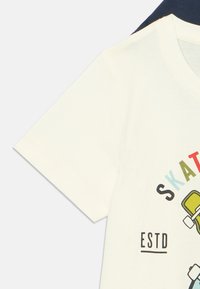 Biała bawełniana koszulka z krótkim rękawem z grafiką skateboardu w kolorze zielonym, czerwonym i niebieskim, z napisem "SKATE" i "ESTD."