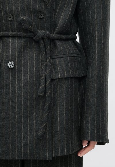 Fekete és szürke csíkos, dupla soros zakó, megkötős övvel, amely texturált anyagból készült, finom zsebbel és kerek fekete gombokkal rendelkezik.