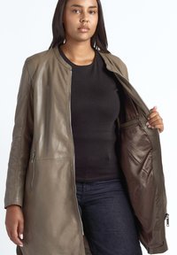Olijfgroene leren jas met ritssluiting, zijzakken en een gladde textuur. Het ontwerp heeft een ronde halslijn en lange mouwen.