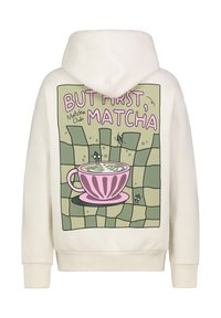 Crème-kleurige hoodie met een grafische print van een roze kopje en de tekst "MAAR EERST, MATCHA" op een groene rasterachtergrond.