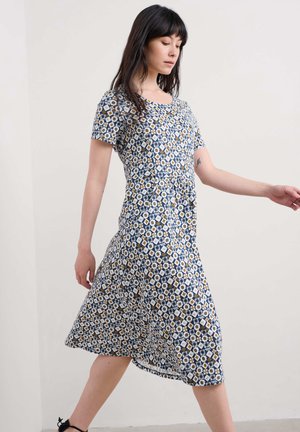 Rochie florală cu mâneci scurte, bază albastră, modele geometrice albe și galbene, lungime până la genunchi, țesătură fluidă și decolteu rotund.
