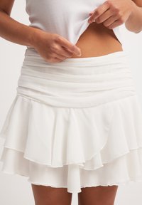 Witte gelaagde mini-jurk gemaakt van lichtgewicht stof, met een gegatherde taille en een gerimpelde zoom voor een vloeiende silhout. 