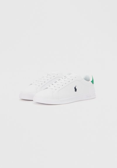 Λευκά αθλητικά παπούτσια χαμηλά με λευκά κορδόνια, πράσινα ταμπελάκια στη φτέρνα και μαύρο λογότυπο παίκτη πόλο στο πλάι, σε κλίση πάνω σε απλό φόντο.