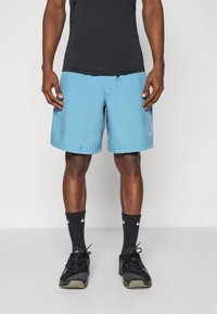 Blue athletic shorts made of lightweight fabric with a straight fit, featuring side pockets and a subtle graphic accent on the side.