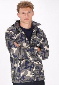 Giacca mimetica in grigio, blu navy e crema, con chiusura a zip frontale, colletto alto, polsini elastici e due tasche laterali. Materiale leggero.