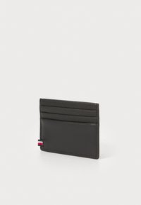 Tarjetero de cuero negro con cuatro ranuras para tarjetas y un pequeño acento de logo. Textura suave, diseño delgado, adecuado para un almacenamiento fácil.
