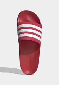 Röd halksandaler gjorda av texturerad gummi med tre vita horisontella ränder. Har en formad fotbädd med präglad logotyp på sulan.