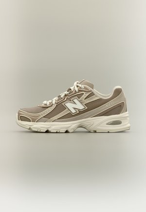 Beige och vit New Balance 740 sportig sko med snörning framtill och vadderad sula, visad i sidoprofil mot en neutral bakgrund.