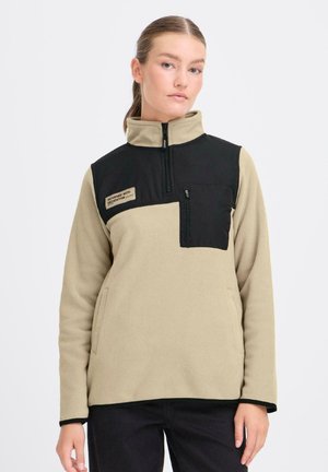 Fleecetröja med en beige kropp och svart övre del, med en halv dragkedja vid kragen, bröstficka och sidofickor. Strukturerad tyg med släta detaljer.