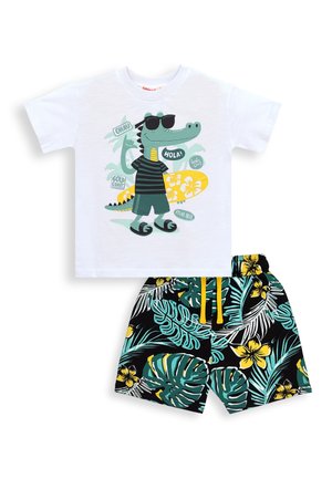 Chemise blanche à manches courtes avec crocodile dessiné en lunettes de soleil et planche de surf, associée à un short noir à motifs floraux avec des feuilles tropicales vertes et jaunes.