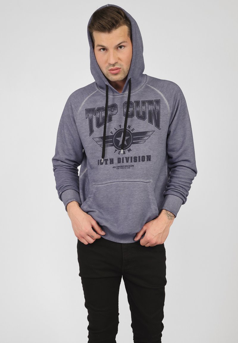 Grå hoodie med frontficka, prydd med grafiskt tryck "TOP GUN" och stjärninsigne. Svarta snören, ribbade muddars och nederkant.