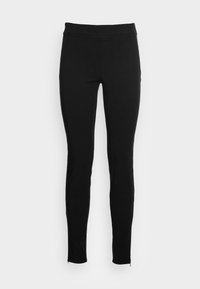 Leggings negros con una textura suave, diseño ajustado y cremalleras en los tobillos. Fabricados con un tejido flexible para facilitar el movimiento.