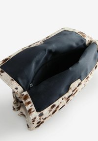 Leopard-print faux fur handbag with a black interior lining and zip closure. Features a rounded shape and a textured exterior.