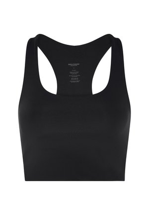 Kvinde i sort sportstøj udfører en knælende bagoverbøjning yogastilling, når hun rækker den ene arm opad og holder sin ankel med den anden hånd.