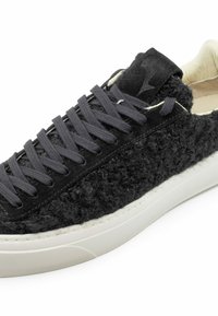 Sneaker nera con tomaia in lana testurizzata, lacci grigi e suola in gomma bianca. Presenta un logo discreto sul tallone e dettagli di cucitura a contrasto.