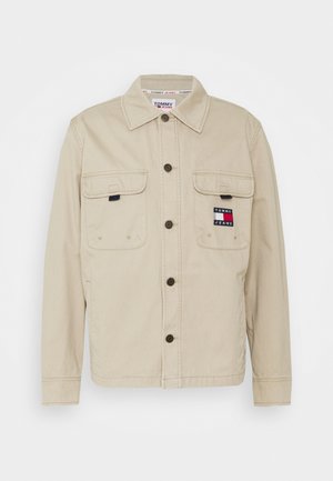 Beige button-up jacket with collar, two front flap pockets, and a Tommy Jeans logo patch on the left chest pocket.