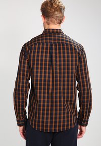 Chemise à manches longues à carreaux bleu marine et orange, dotée d'un col boutonné, d'un ourlet droit et de poignets boutonnés. Tissu en mélange de coton.